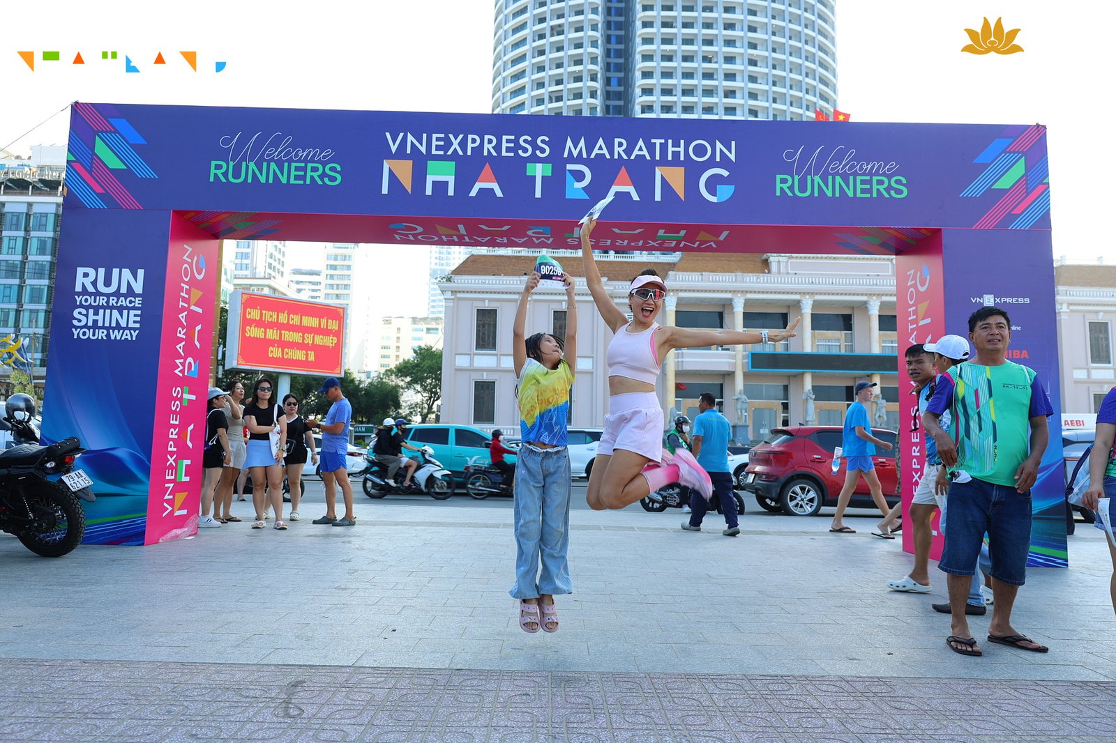 Vợ và con gái Phạm Đức Anh nhảy lên vui mừng, giơ cao bib 90259 tại cổng chào VnExpress Marathon Nha Trang